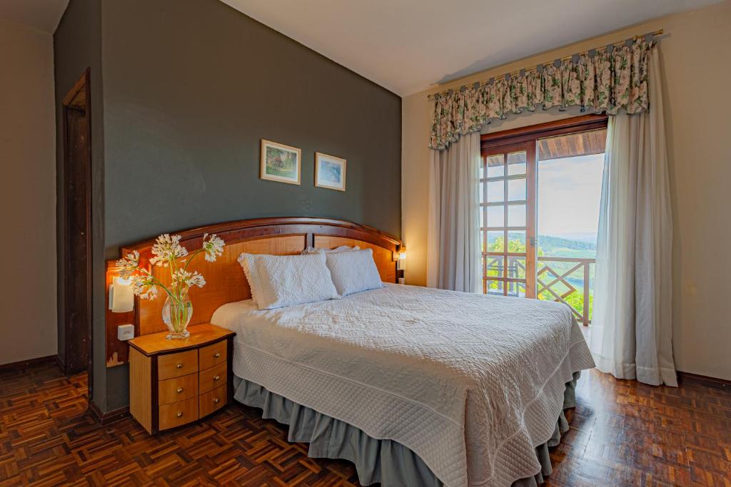a bedroom with a bed and a large window at Hotel Spaço Vale do Jordão in Guarapuava