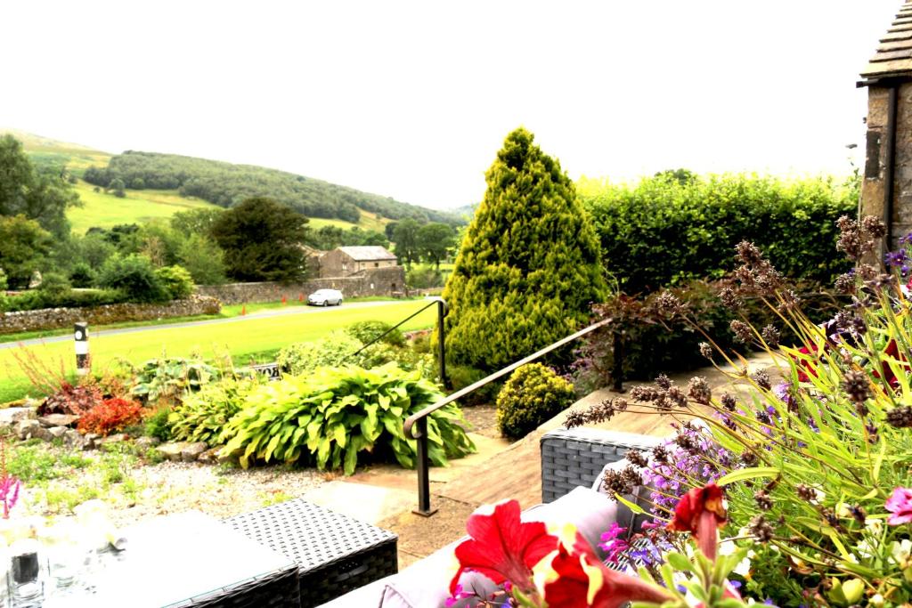 a garden with flowers and a view of a house at Romany Cottage B&B in Buckden