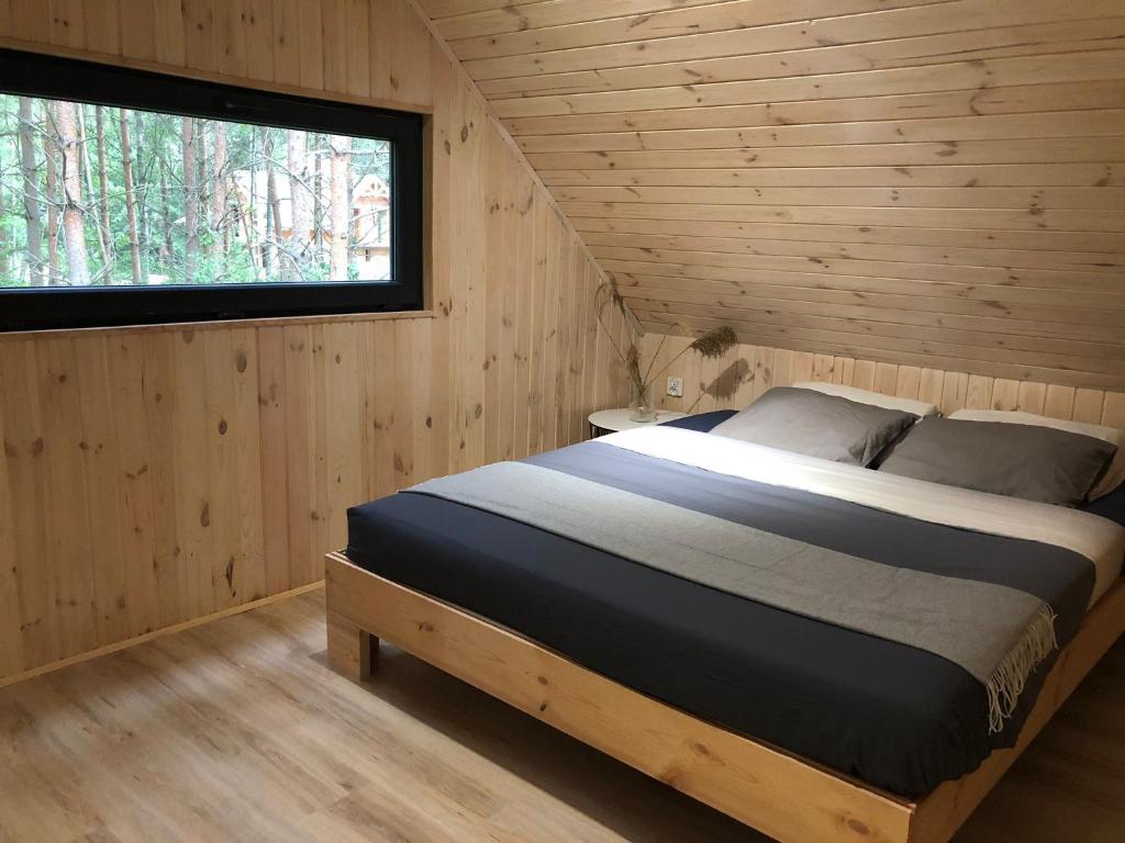 - une chambre avec un lit dans une cabane en bois dans l'établissement Domki Trzy, à Krzywonoga