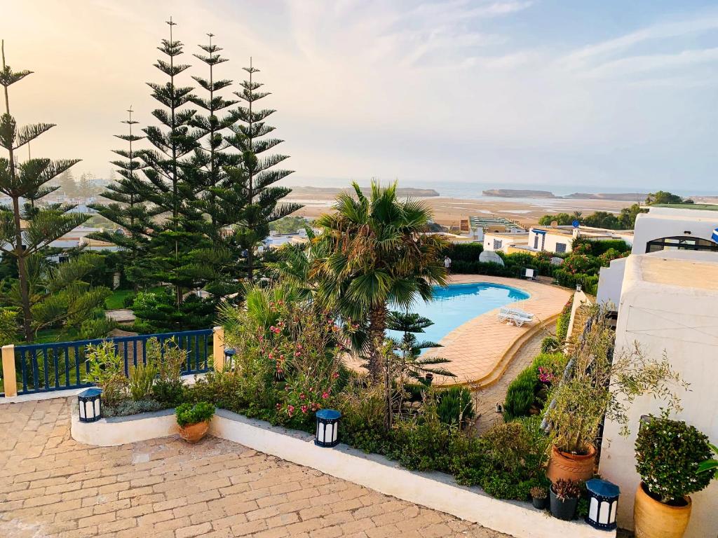 a resort with a swimming pool and a palm tree at Maison Oualidia Vue sur Mer-Jardins de la Lagune in Oualidia