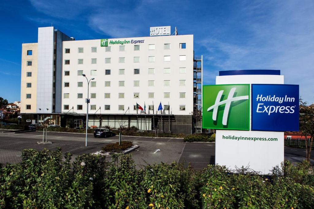 Holiday Inn Express Lisbon-Oeiras, an IHG Hotel في أويراس: مبنى ابيض كبير امامه لافته