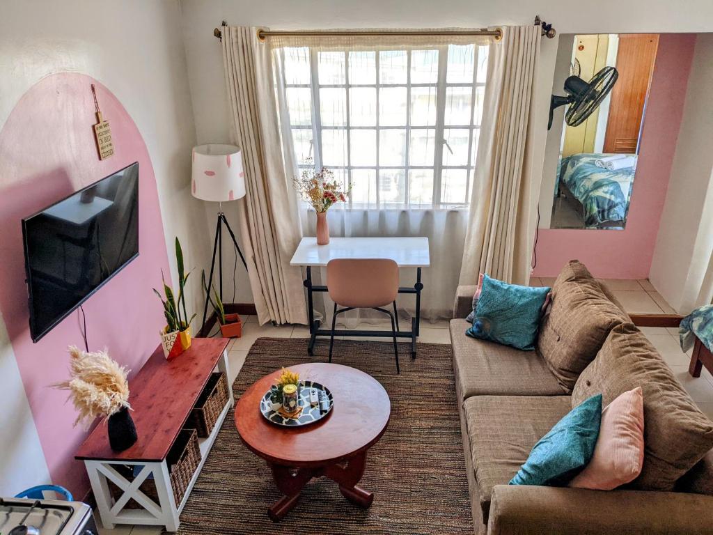 een woonkamer met een bank en een tafel bij Home and Away Cozy Studio Apartment number 407 in Nairobi