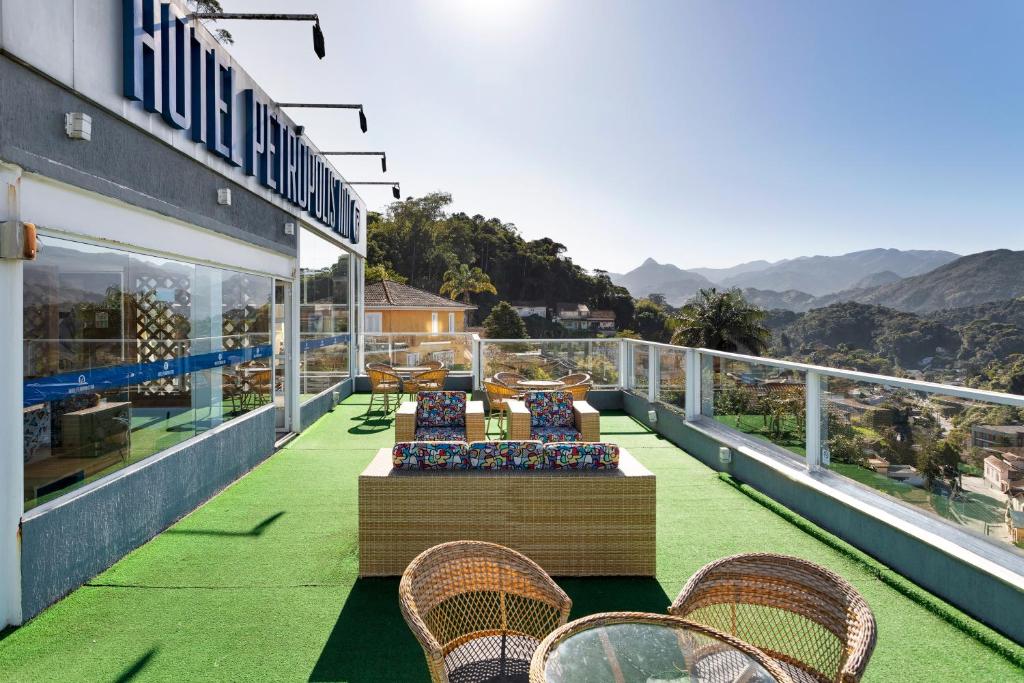 a balcony with chairs and tables and mountains in the background at Hotel Petropolis Inn in Petrópolis