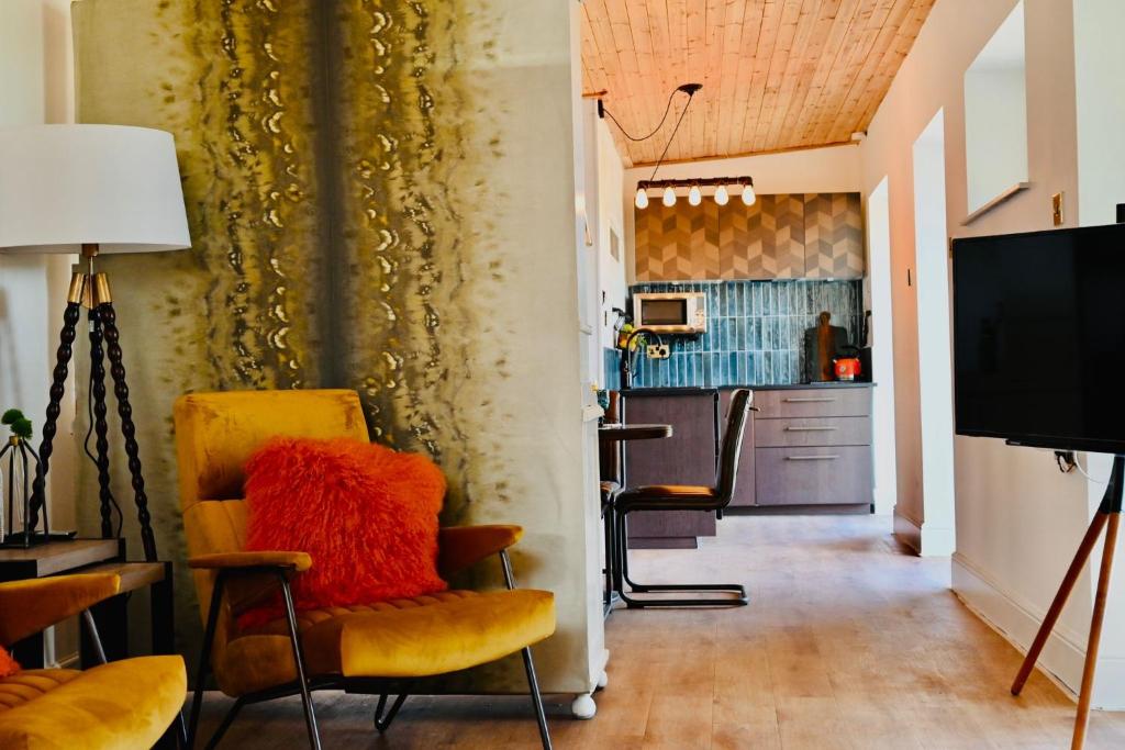 The Stables Hideaway في ليانيلي: غرفة معيشة مع كراسي صفراء ومطبخ