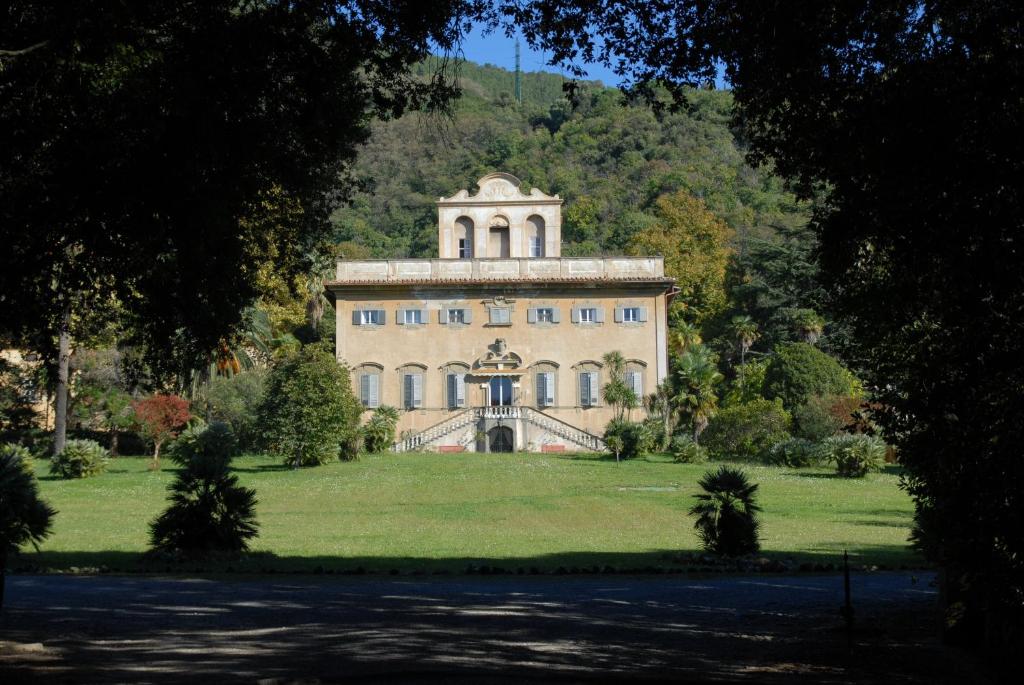 un grand bâtiment sur un champ herbeux planté d'arbres dans l'établissement Villa di Corliano Relais all'Ussero, à San Giuliano Terme