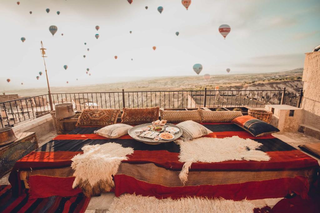 a bed on top of a balcony with hot air balloons at Vasıl Cave Hotel in Uchisar