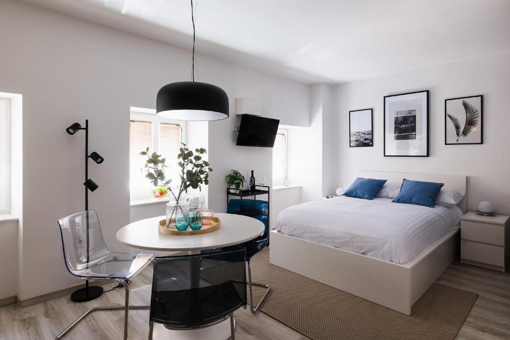 a white bedroom with a bed and a table and chairs at New Central Studios with parking in Ljubljana