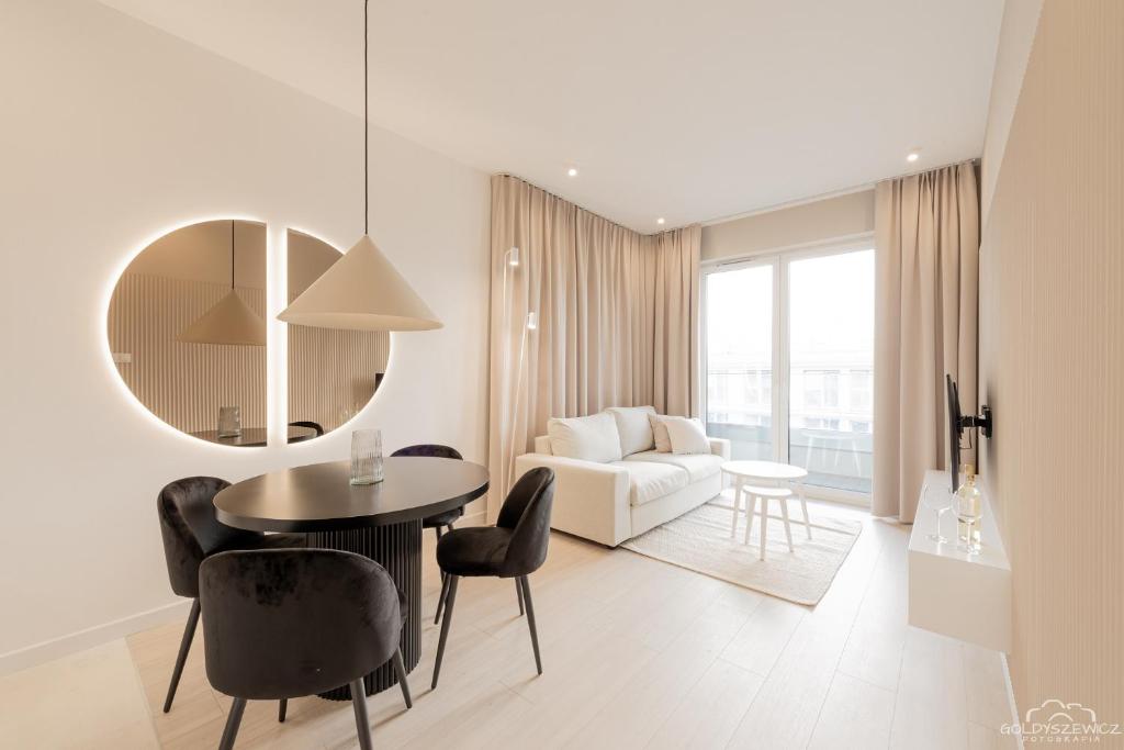 a white living room with a table and a mirror at Kołobrzeg Harmony Apartments in Kołobrzeg