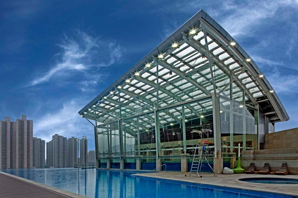 a large glass building next to a swimming pool at Nina Hotel Tsuen Wan West in Hong Kong