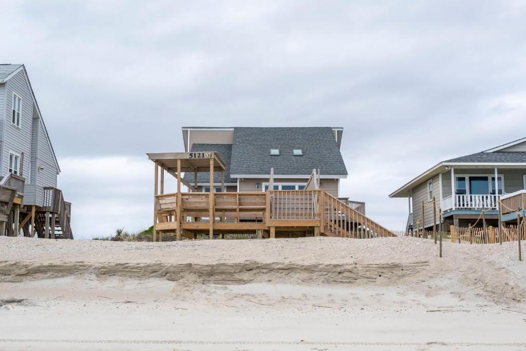 a house on the beach next to some houses at Wahoo by Oak Island Accommodations in Oak Island