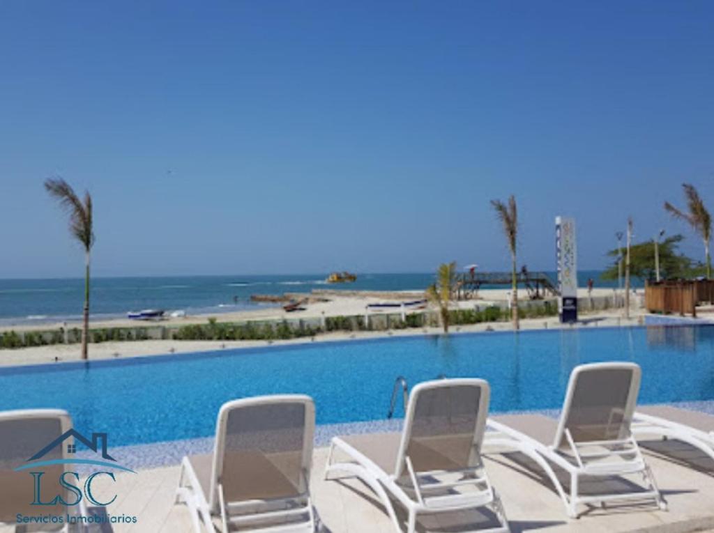 a group of lawn chairs sitting next to a swimming pool at Club de Playa Samaria - T1 APTO 1705, Santamarta in Santa Marta