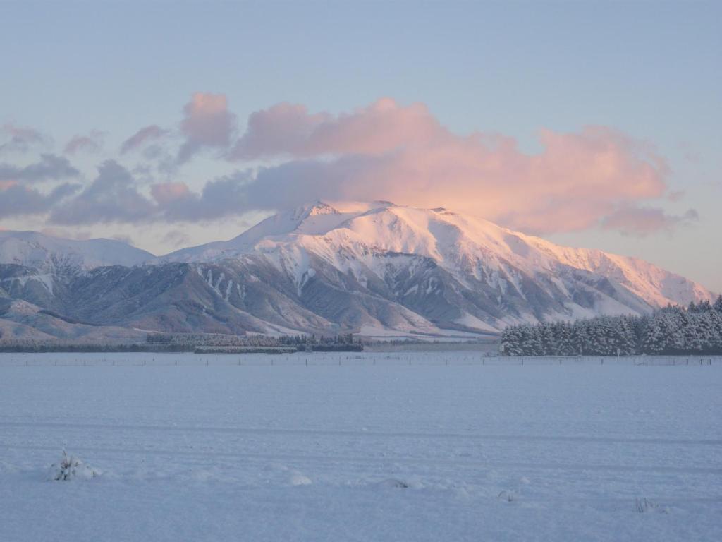 a snow covered mountain in front of a large body of water at Ski Time in Methven