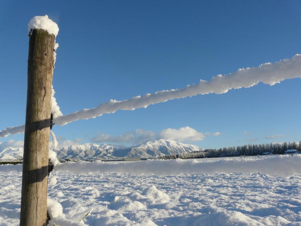 a barbed wire fence in the snow with a mountain at Ski Time in Methven