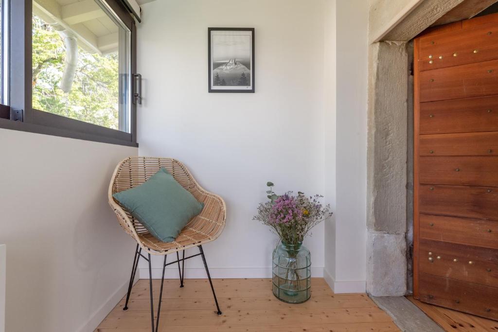 a wicker chair in a hallway with a vase of flowers at Les Tours Carrées in La Motte-Servolex