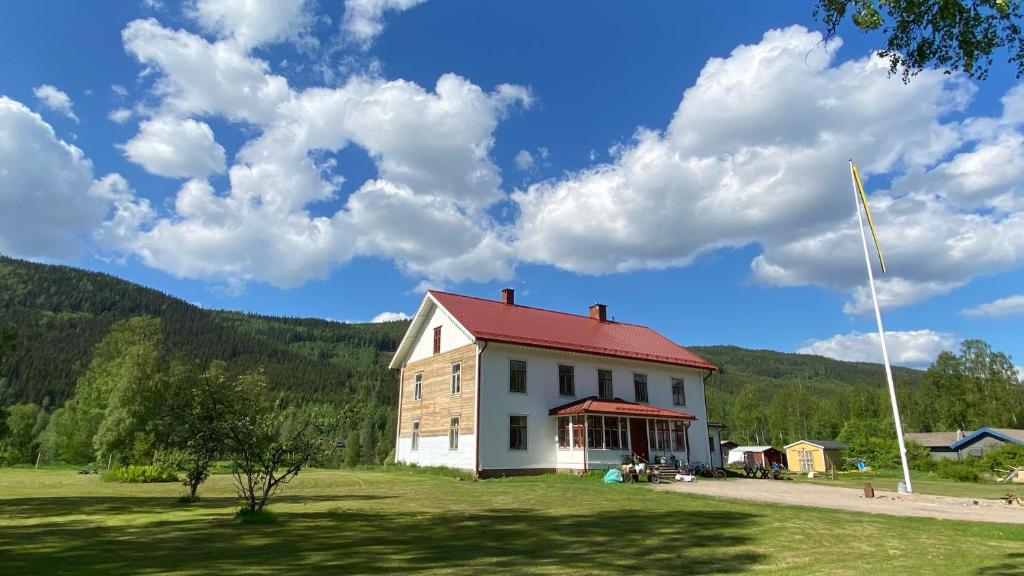 a white house with a red roof on a field at Mysig lägenhet i Prästgård nära Branäs in Sysslebäck