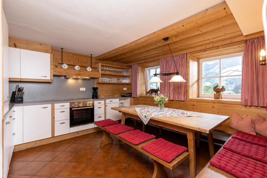 a kitchen with a wooden table and red chairs at Chalet Dorfbäck in Stumm