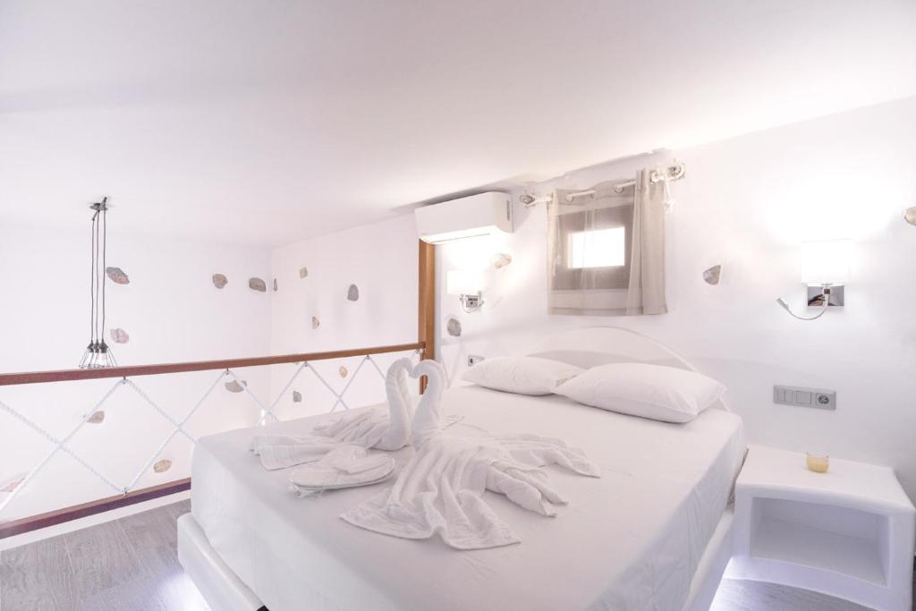 a white bedroom with white towels on a bed at Primrose Apartments in Astypalaia