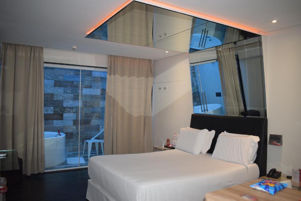 a bedroom with a white bed and a large window at Eros Hotel CDU (Adults Only) in Recife