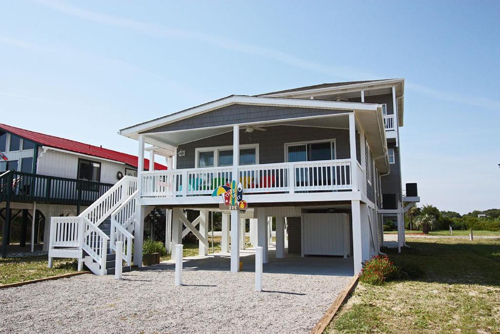 a house with a white deck and a porch at This Is It by Oak Island Accommodations in Oak Island