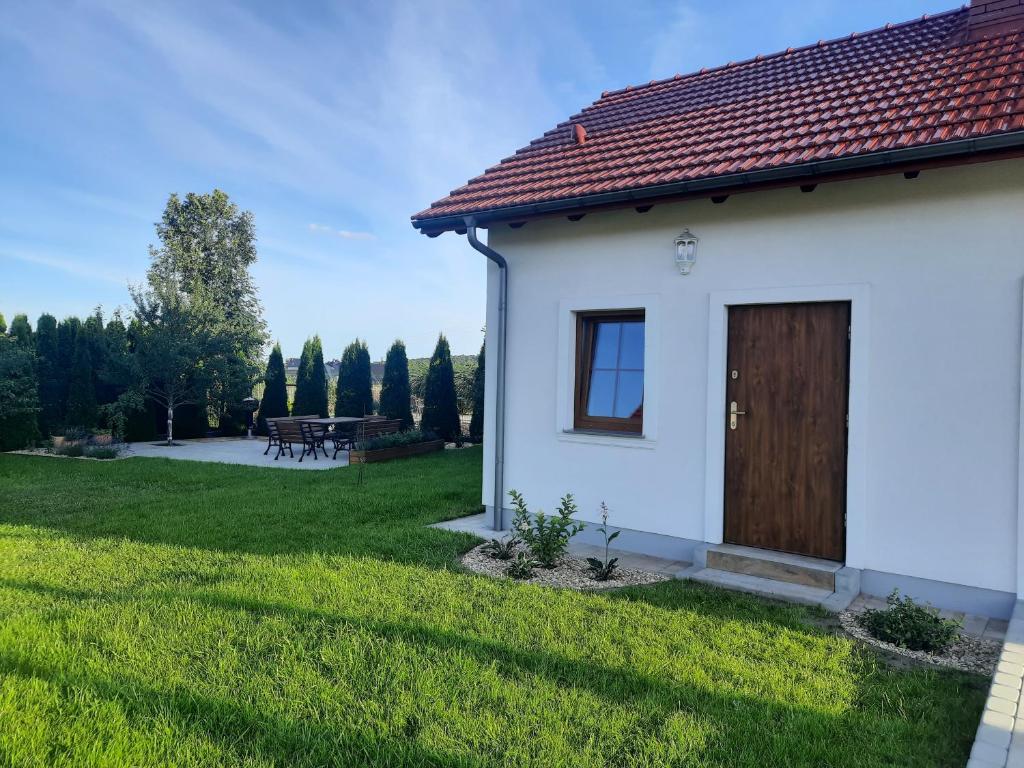 a white house with a wooden door in a yard at Apartament w Chęcinach in Chęciny