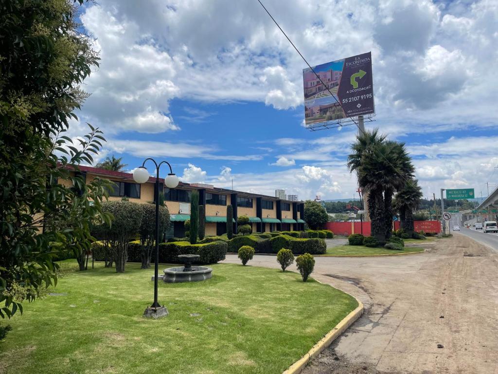 a building on a street with a sign in the grass at Hotel Lerma in Lerma de Villada