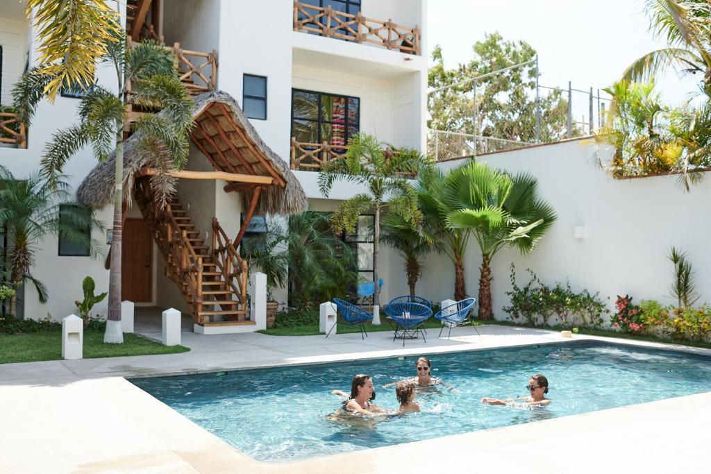 a group of people in a swimming pool next to a building at Punta Mita Surf Lodge in Punta Mita