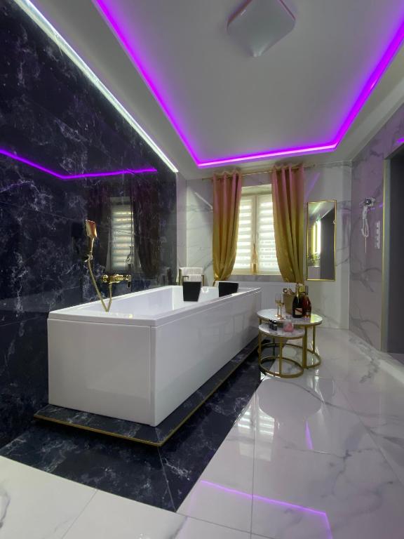 a bathroom with a white tub and purple lighting at Apartament "Prezydencki" Centrum z dużą wanną dla Dwojga in Gniezno