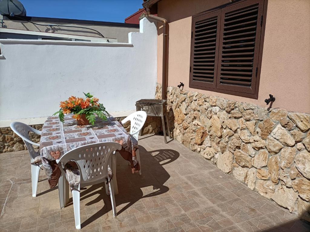 una mesa y sillas en un patio con una pared de piedra en Casa Nonna Pina en Fanusa