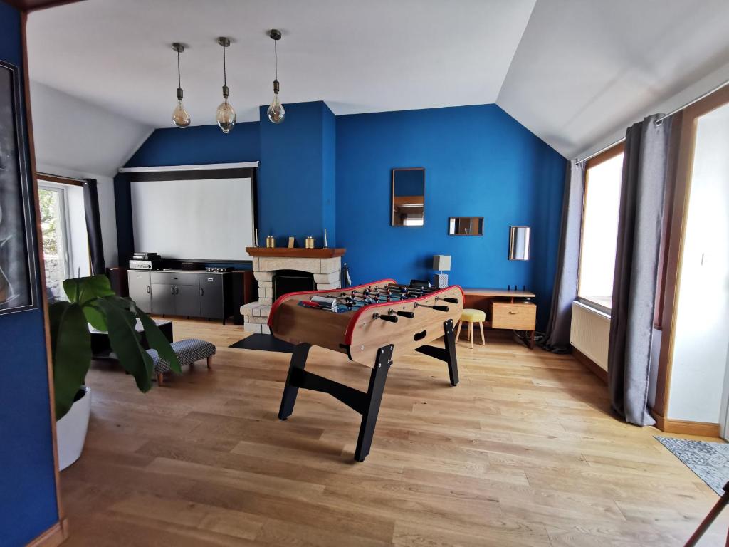 ein blaues Zimmer mit einem Bett und einem Tisch in der Unterkunft Gîte Le Petit Bacchus in Sainte-Croix-Hague