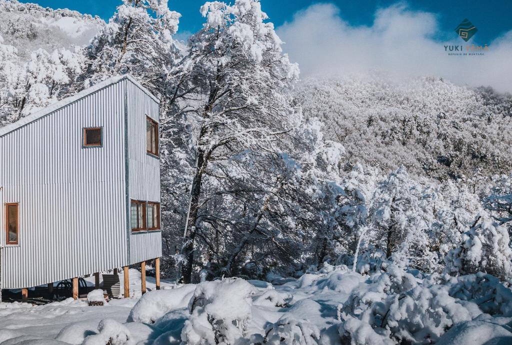 a building covered in snow next to trees at Yuki Yama in Malalcahuello