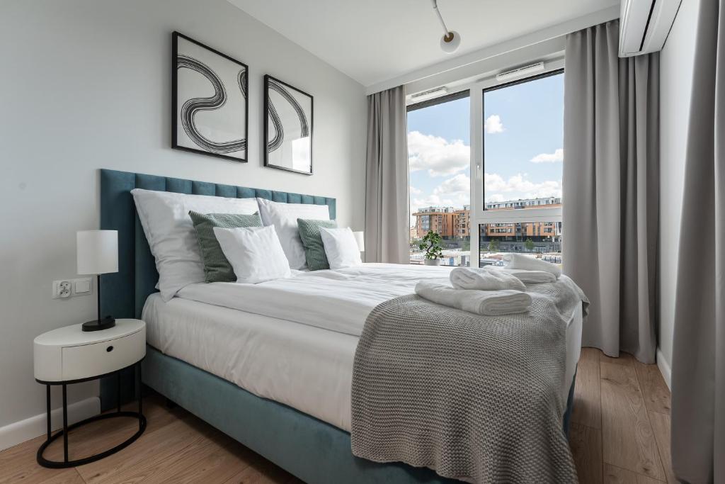 a bedroom with a large bed and a large window at Apartament Chlebova 315 in Gdańsk