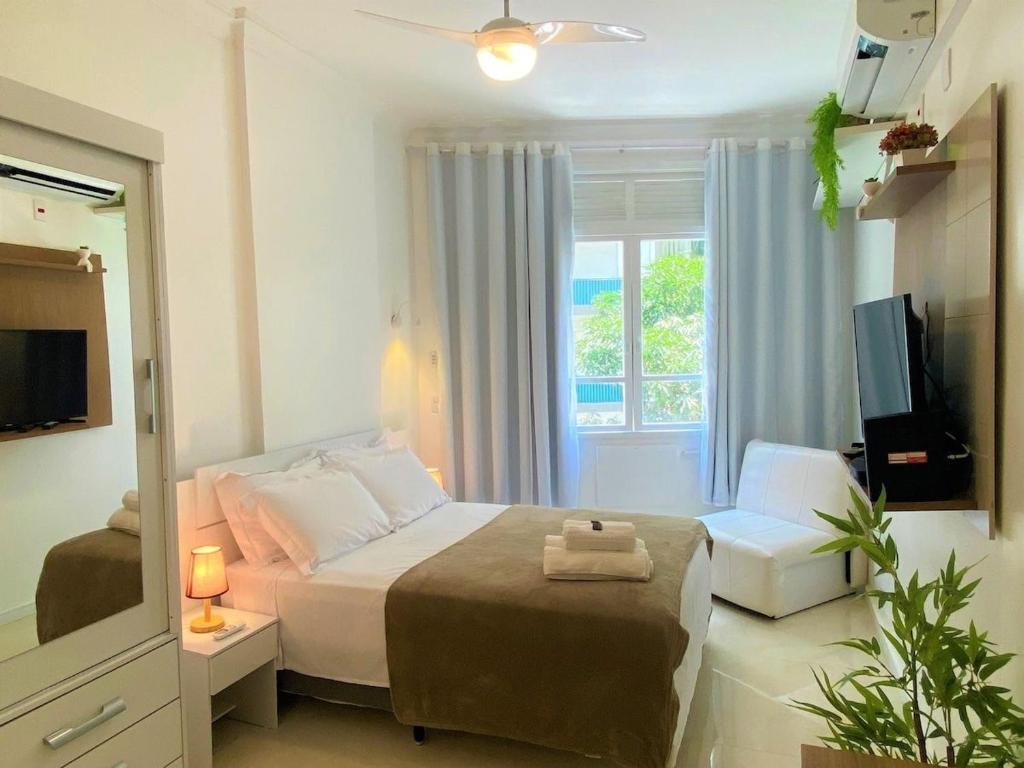 ein Schlafzimmer mit einem Bett, einem Spiegel und einem Fernseher in der Unterkunft M30 - Flat a 3 minutos da praia de Copacabana in Rio de Janeiro
