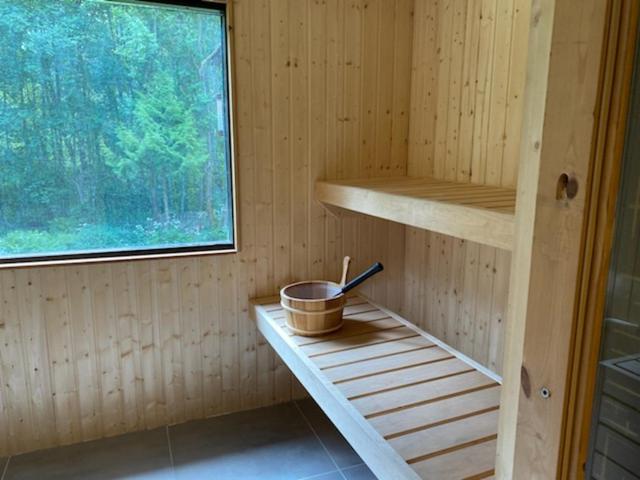 a wooden sauna with a bucket and a window at Dyreborg Boutique Guesthouse in Knäred
