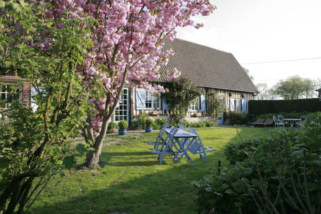 a house with a picnic table and a tree with pink flowers at La Roselière in Sainte-Colombe