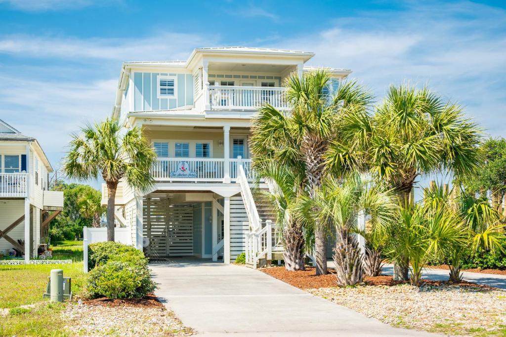 una casa blanca con palmeras y una acera en The Anchor Holds by Oak Island Accommodations en Oak Island