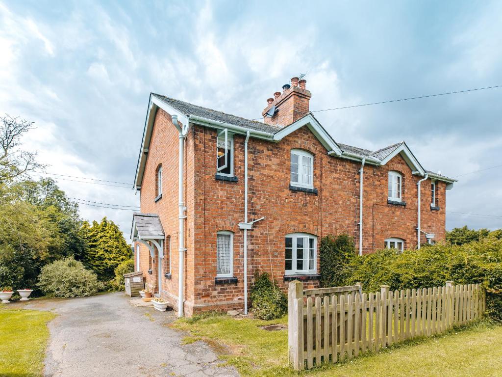 a brick house with a fence in front of it at Eudon Burnell Cottage in Eardington