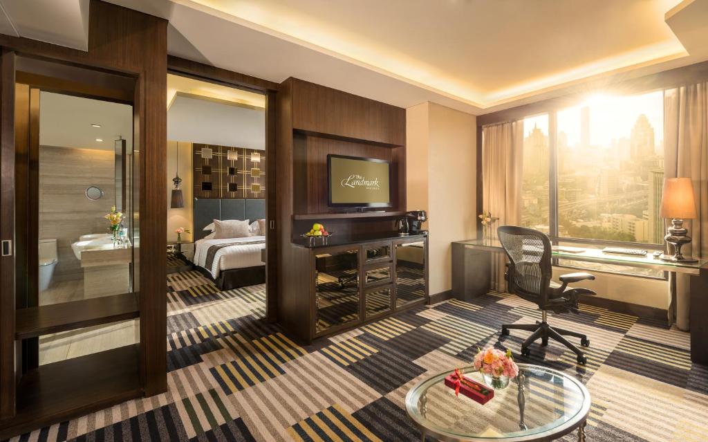 ein Hotelzimmer mit einem Bett, einem Schreibtisch und einem TV in der Unterkunft The Landmark Bangkok - SHA Extra Plus in Bangkok