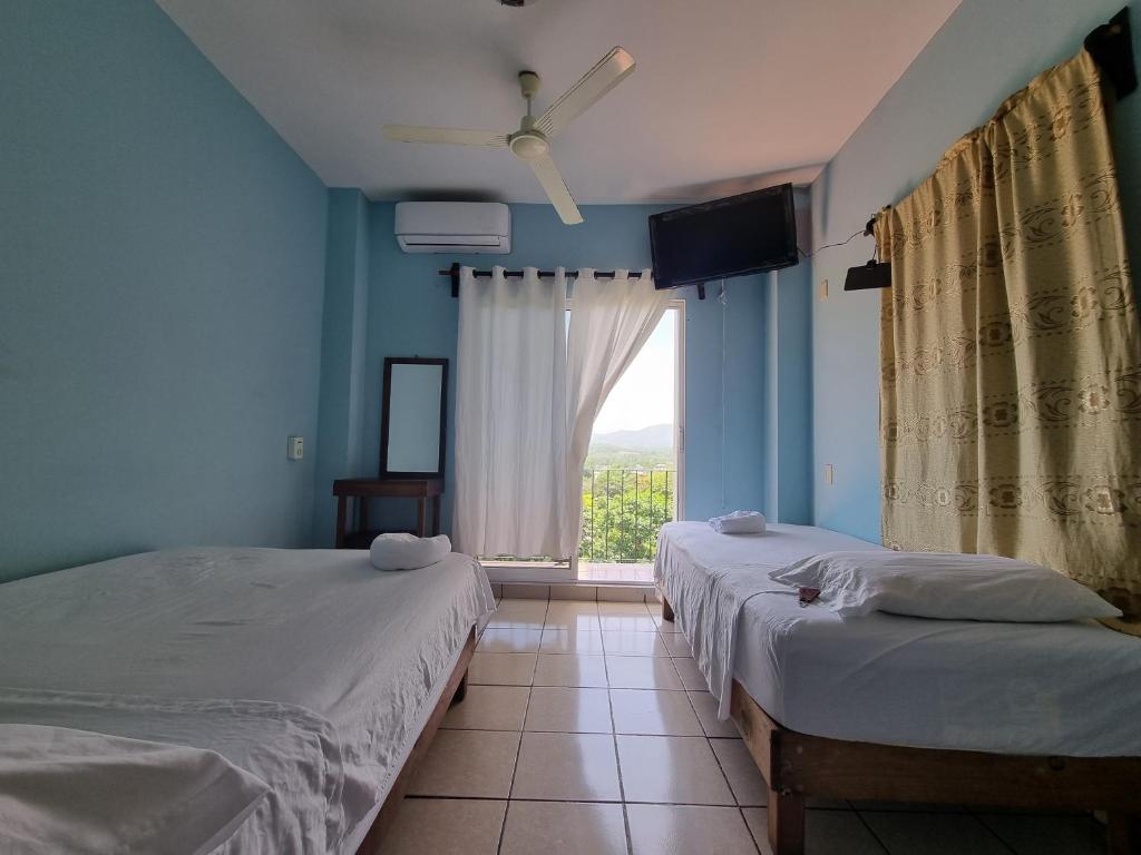 a bedroom with two beds and a window with a view at Casa La Paz 3 in Puerto Escondido