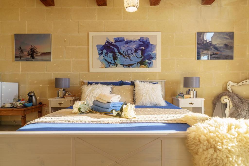 a bedroom with a large bed with blue and white sheets at Ajuga Luxury Boutique B&B in Qala