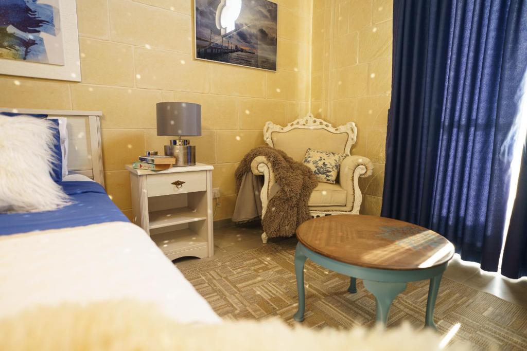a bedroom with a bed and a table and a chair at Ajuga Luxury Boutique B&B in Qala