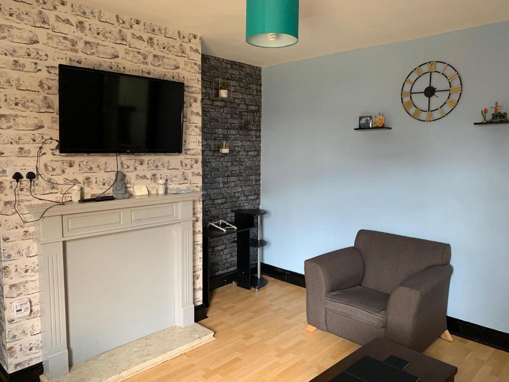 a living room with a chair and a television on a wall at Ovington Grove 1 free parking fully equipped kitchen 3 bedrooms Netflix in Newcastle upon Tyne