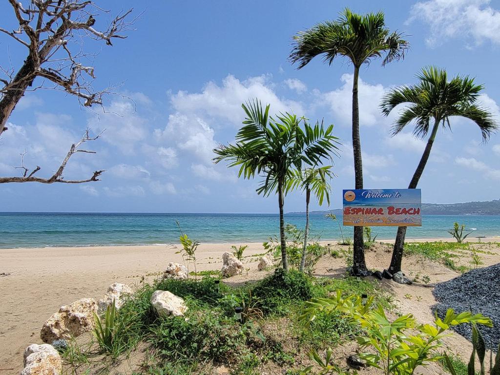 a sign on a beach with palm trees and the ocean at Aguada of the Seas in Aguada