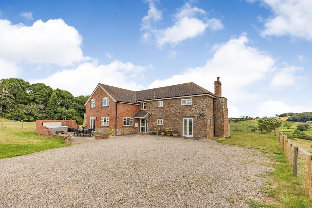 a large brick house with a gravel driveway at Wood Cottage in Tenbury