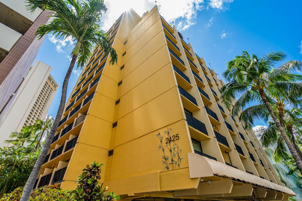 ホノルルにあるThe Bamboo Oasis at Bamboo Waikiki #307のヤシの木が目の前に広がる黄色い建物