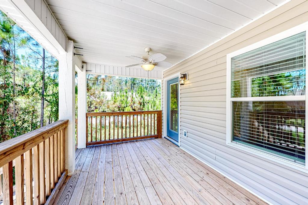 a house with a porch with a ceiling fan at Beach Cottage East in Dauphin Island