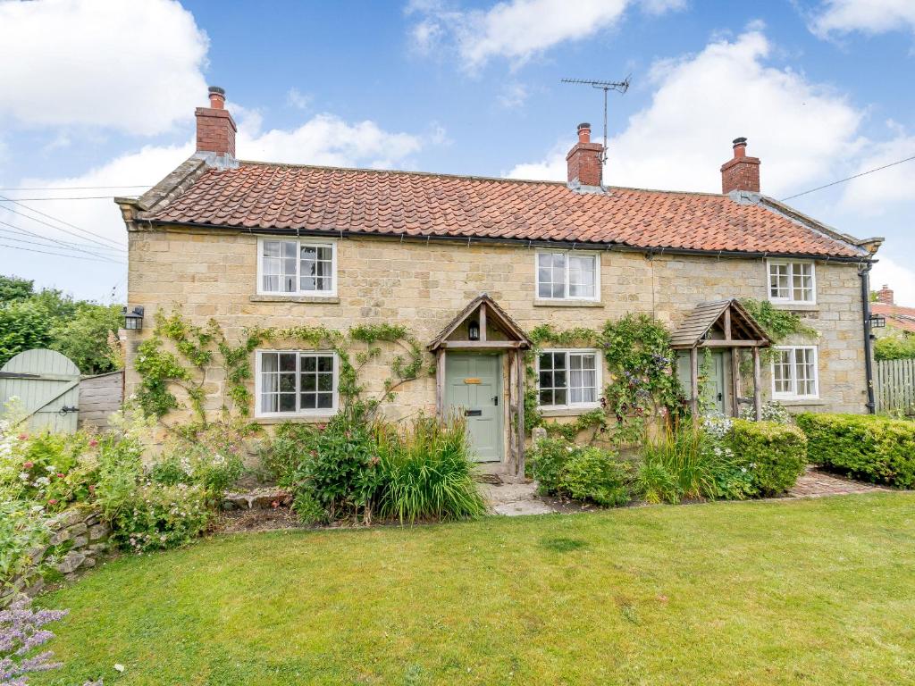 an old stone house with a garden in front of it at Corner Cottage in Pickering