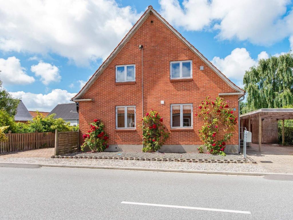 a red brick house with flowers in front of a street at 10 person holiday home in Ulfborg-By Traum in Ulfborg