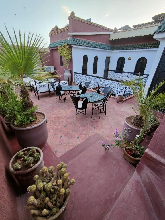 a patio with tables and chairs and potted plants at Riad Assalam in Marrakech