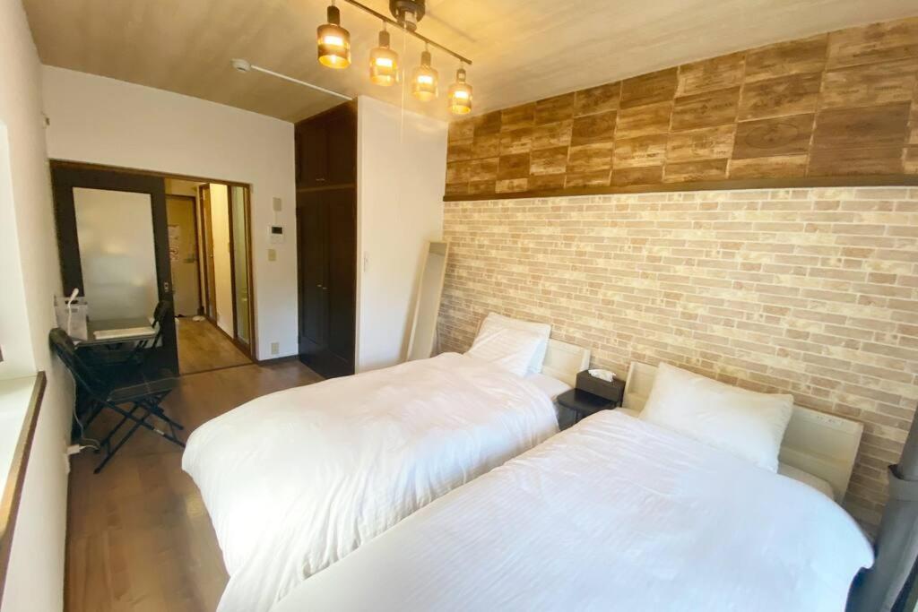 a bedroom with two beds and a brick wall at ラ・ポート空港前107 in Shime