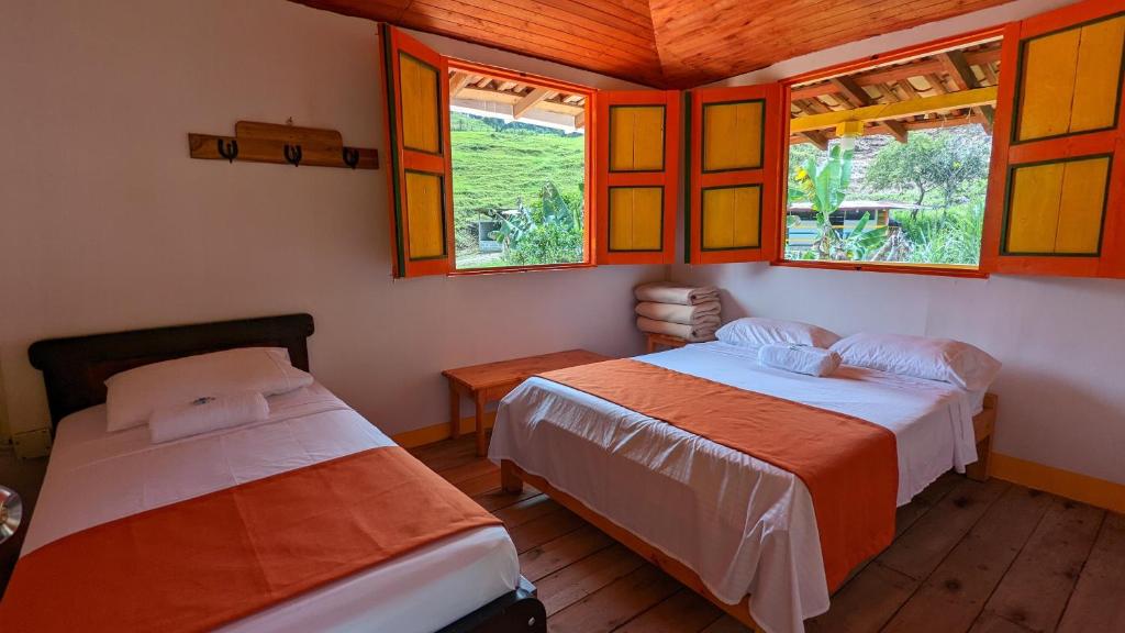 two beds in a room with windows at Hospedaje Campestre El Rancho de Jero in Jardin